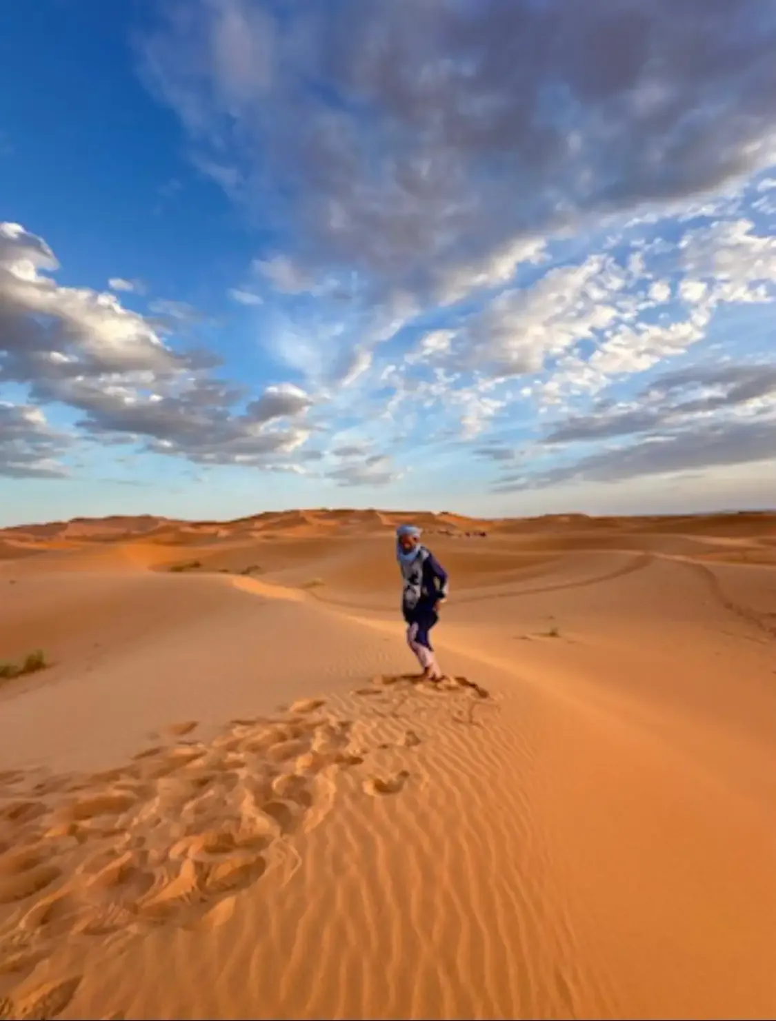 Silhouette d’un voyageur marchant seul sur les dunes de l’Erg Chebbi, sous un grand ciel bleu