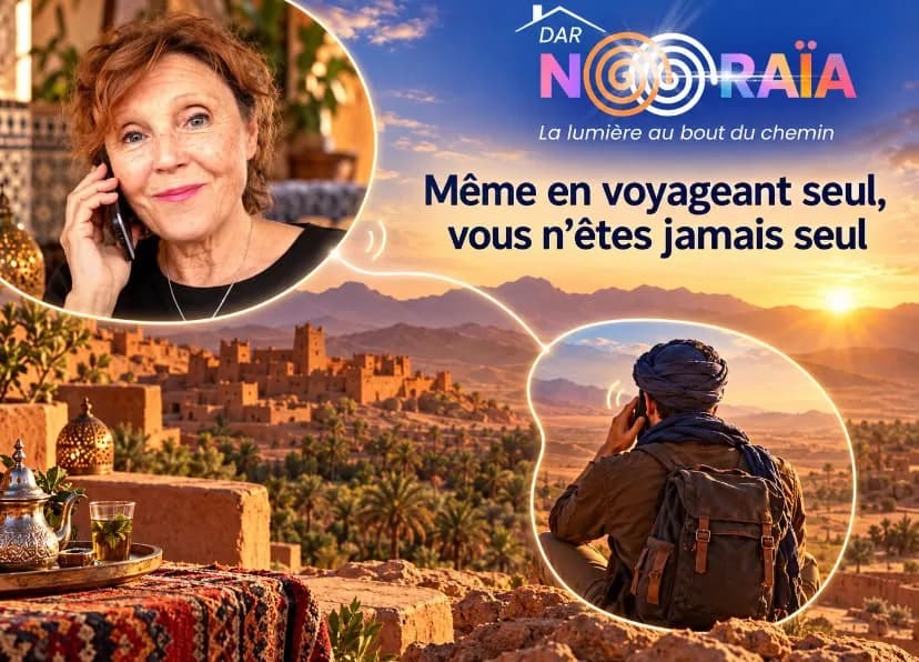 Dominique au téléphone avec un voyageur assis face à une kasbah au coucher du soleil — « Même en voyageant seul, vous n’êtes jamais seul »